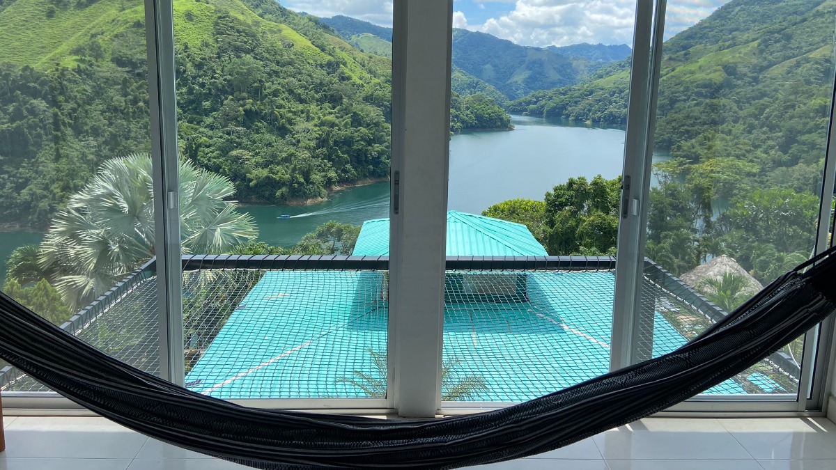 Habitación deluxe con hamaca y ventanal panorámico hacia el embalse y la piscina